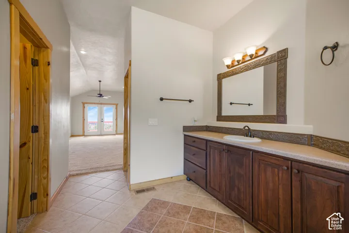 Vaulted ceiling with a ceiling fan, French doors, wood-finish flooring, and a vanity with a surface-mount sink