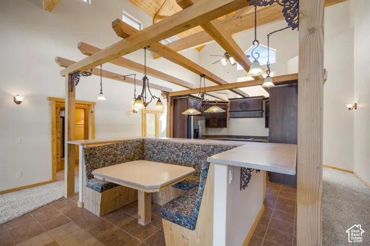 Vaulted ceiling with exposed wood beams, built-in booth seating, tile flooring, and integrated overhead lighting