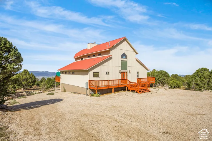 Multi-level exterior with a red roof, a wooden deck, and an expansive gravel area