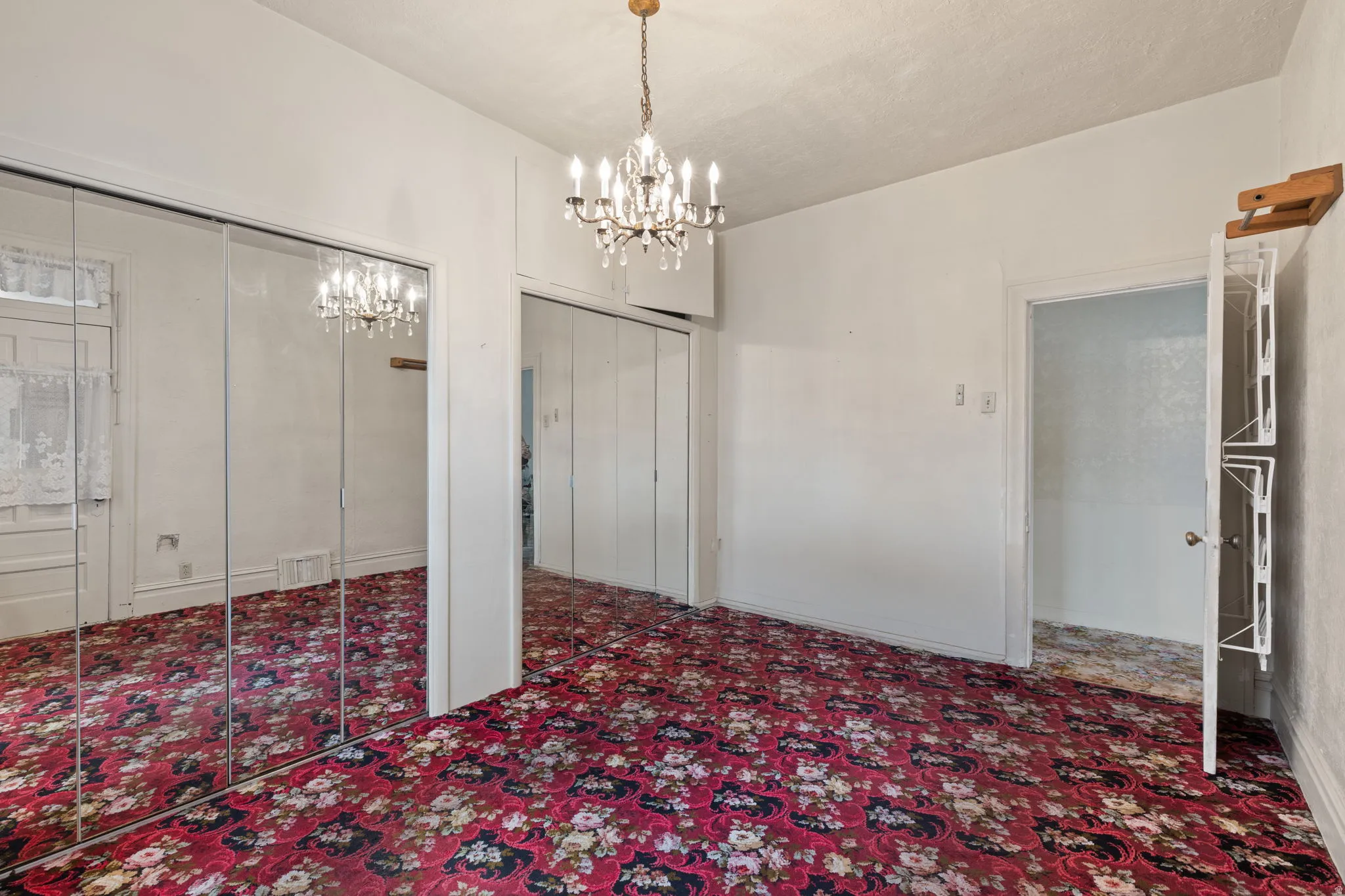Chandelier lighting, mirrored closet doors, and additional closet space