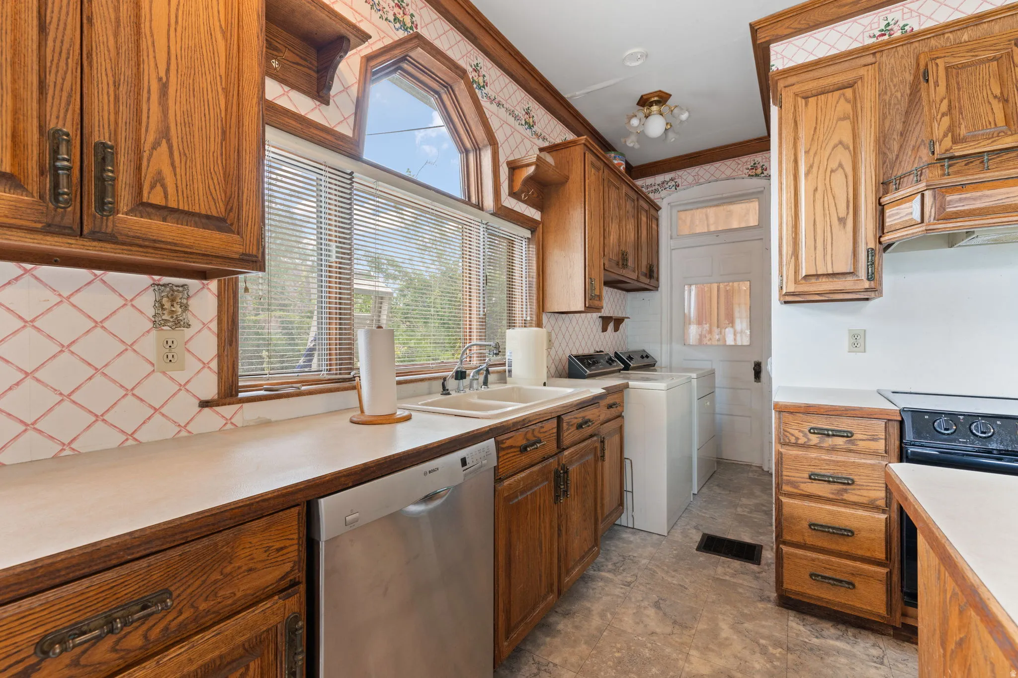 Kitchen featuring wood cabinetry, white countertops, a stainless steel dishwasher, and a double basin sink