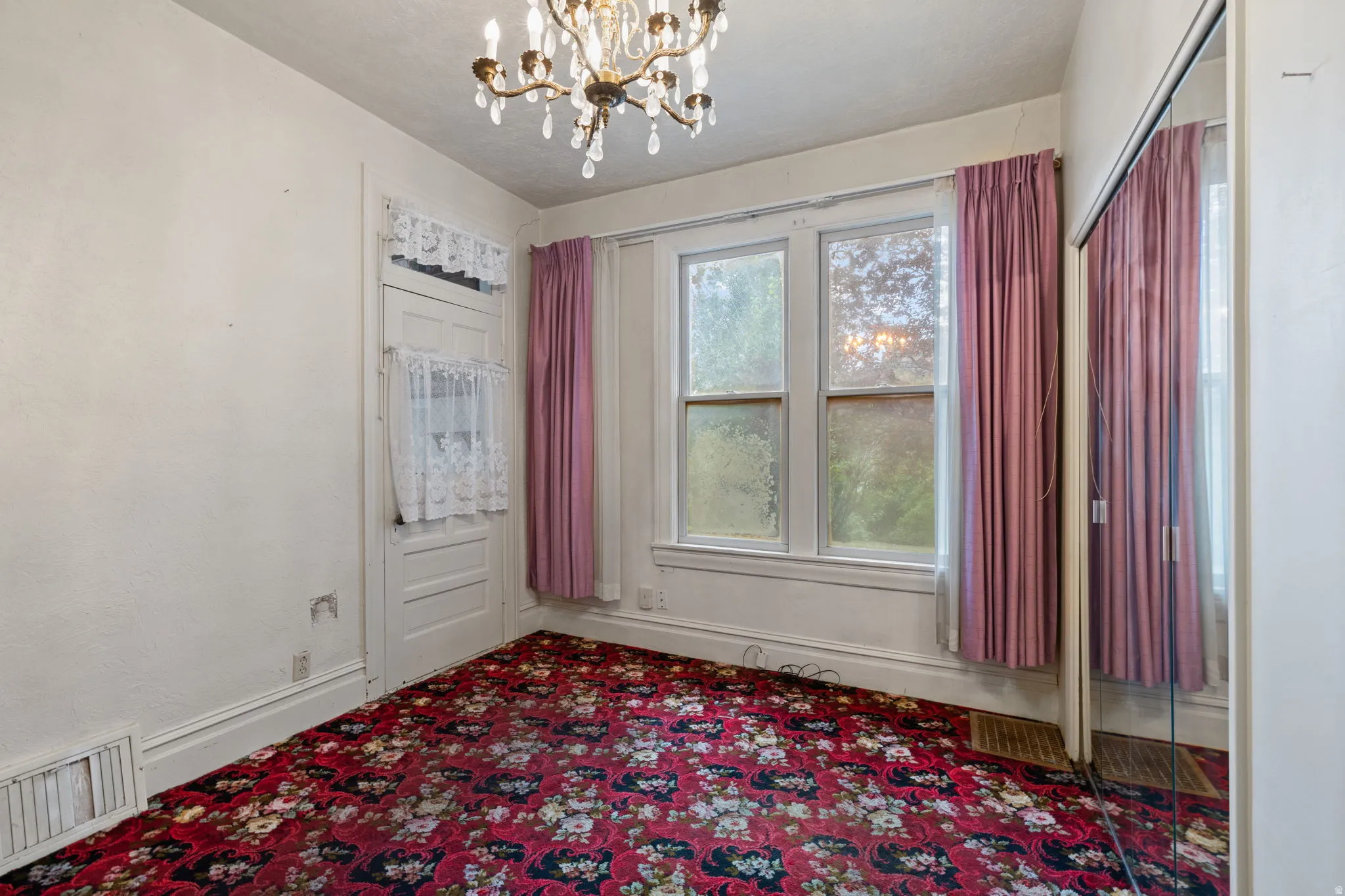 Chandelier lighting, three-pane window, white trim, mirrored closet doors, and patterned carpet