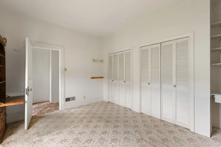 White louvered bi-fold doors, built-in shelving, wood-finish built-in desk, and a painted paneled door