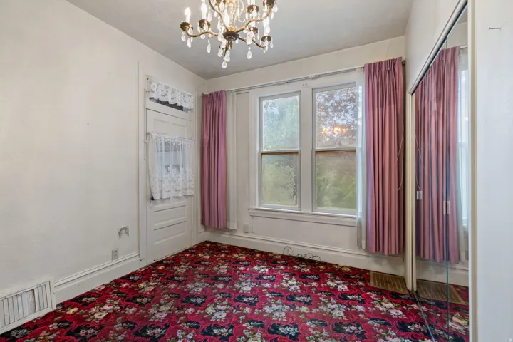 Chandelier lighting, three-pane window, white trim, mirrored closet doors, and patterned carpet