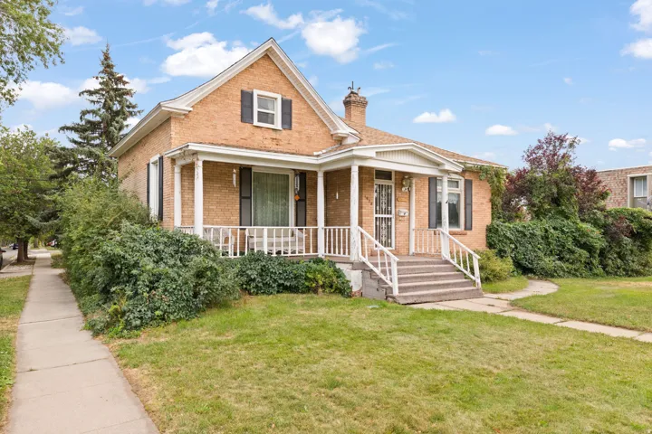 Brick exterior with white trim, covered porch, multiple windows, and a landscaped front yard