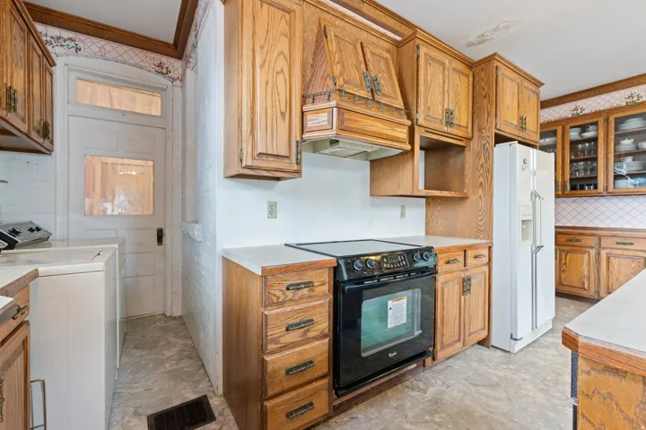 Wood cabinetry with varied storage options, white countertops, and a black electric range