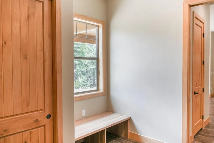 Bright alcove with a substantial window seat featuring wood-finish trim, natural light from a multi-pane window, and solid wood doors with traditional hardware framing the space