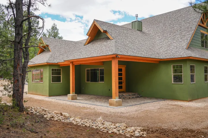 Green stucco exterior with exposed wood structural elements