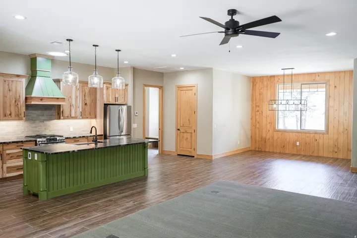 Kitchen island with a green beadboard finish, wood-finish flooring, recessed lighting, and a wood-paneled accent wall