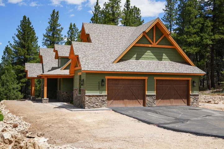 Craftsman-style exterior with green siding, stone accents, and a multi-gabled roof