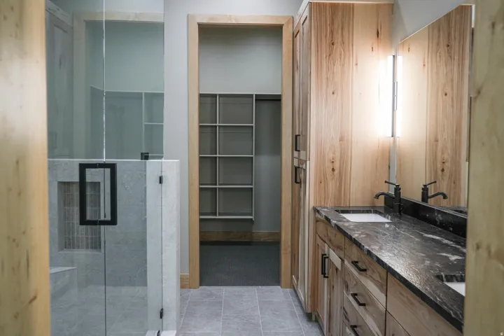 Dual vanity with dark stone countertop, integrated sinks, and black fixtures