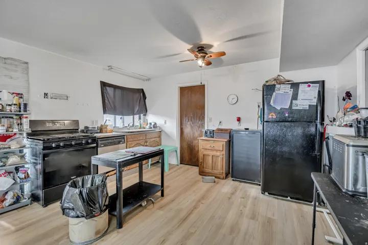 Kitchen featuring wood-finish flooring, a ceiling fan, a gas range, and a stainless steel dishwasher