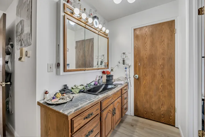 Wood-finish vanity with dark countertop, integrated dark sink, and mirrored medicine cabinet