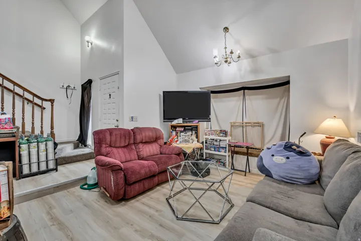 Vaulted ceilings with an exposed beam, wood-finish flooring, and a chandelier fixture