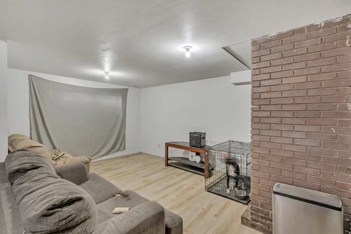 Living area with wood-finish flooring, recessed lighting, and an exposed brick accent wall