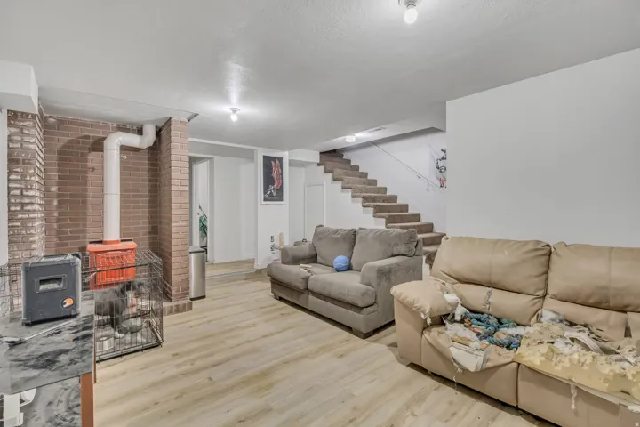 Wood-finish flooring, exposed brick wall feature, and carpeted stairs