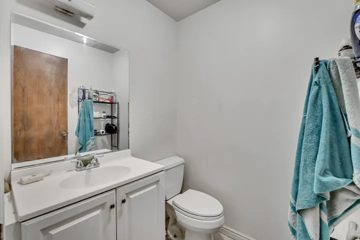 Vanity with integrated sink, wall-mounted mirror, and a toilet