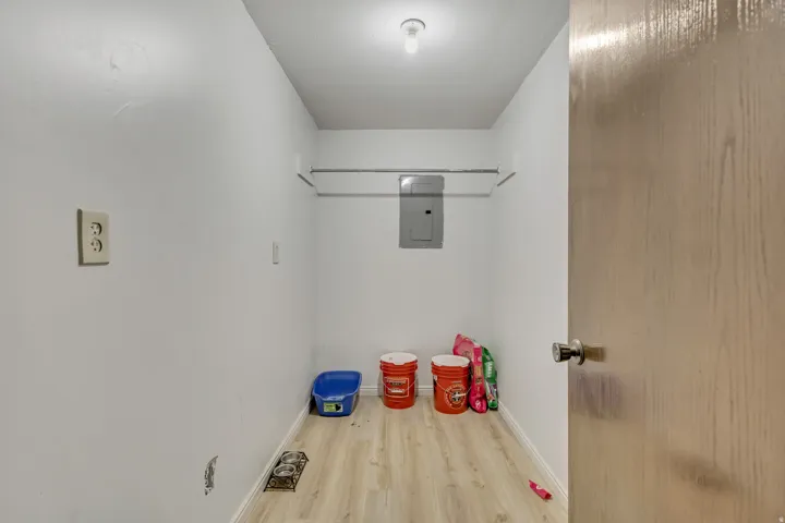 Utility space featuring wood-finish flooring, a wall-mounted electrical panel, and an overhead light fixture