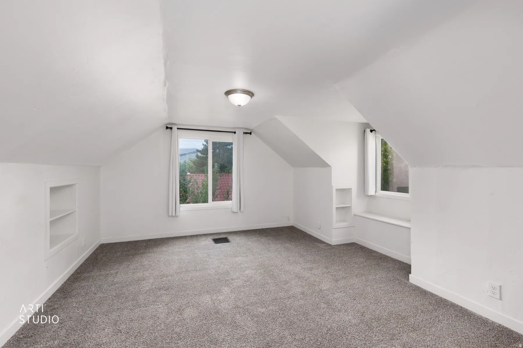 Sloped ceilings with recessed shelving, neutral carpet, and multiple windows