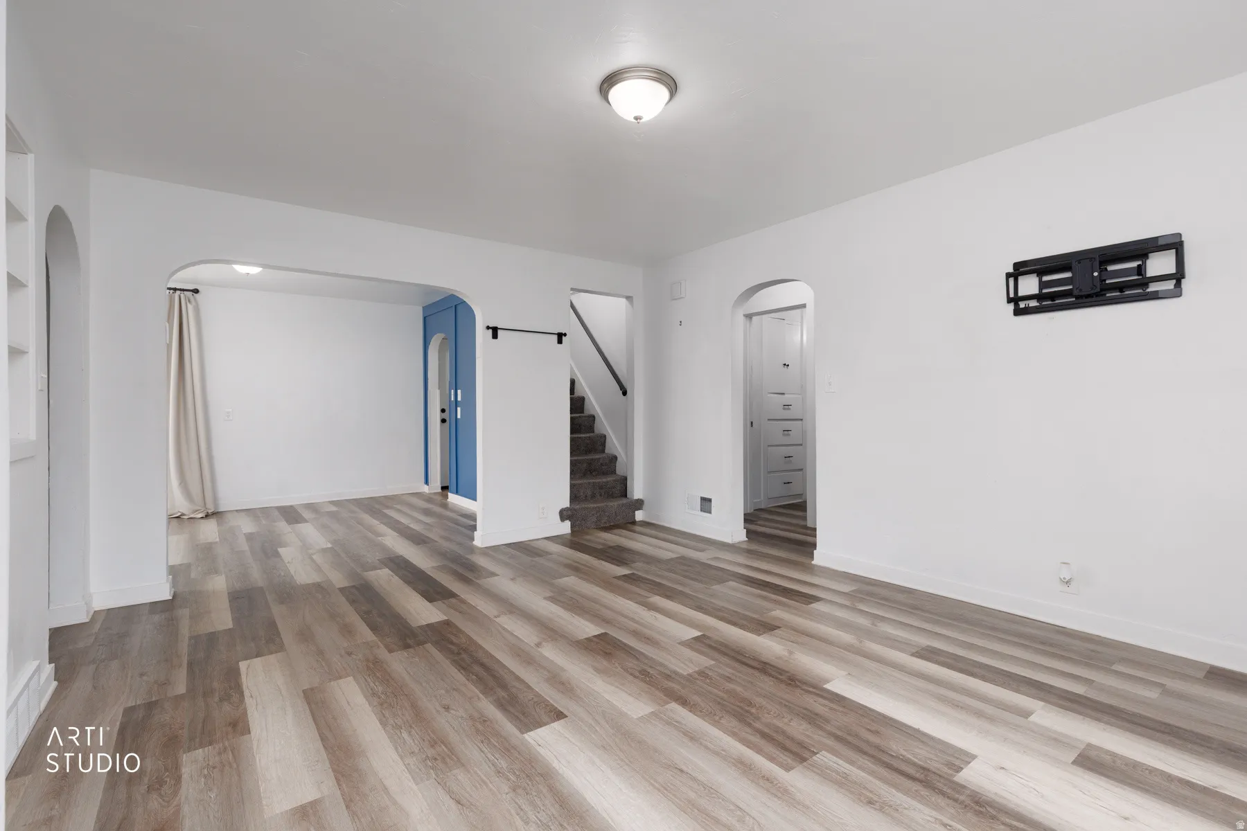 Wood-finish flooring throughout, bright white walls, arched doorways, and a built-in media mount