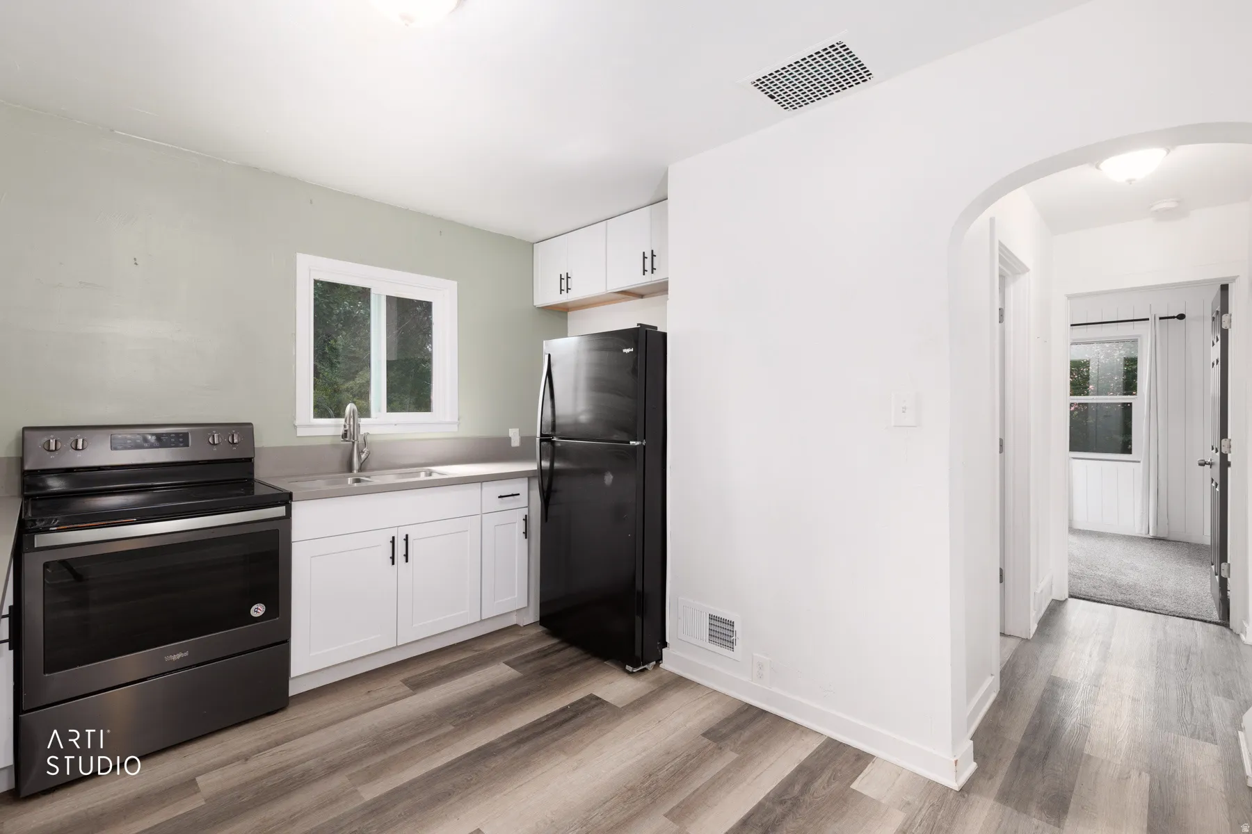 Modern kitchen featuring white cabinetry, gray countertops, stainless steel appliances, and wood-finish flooring