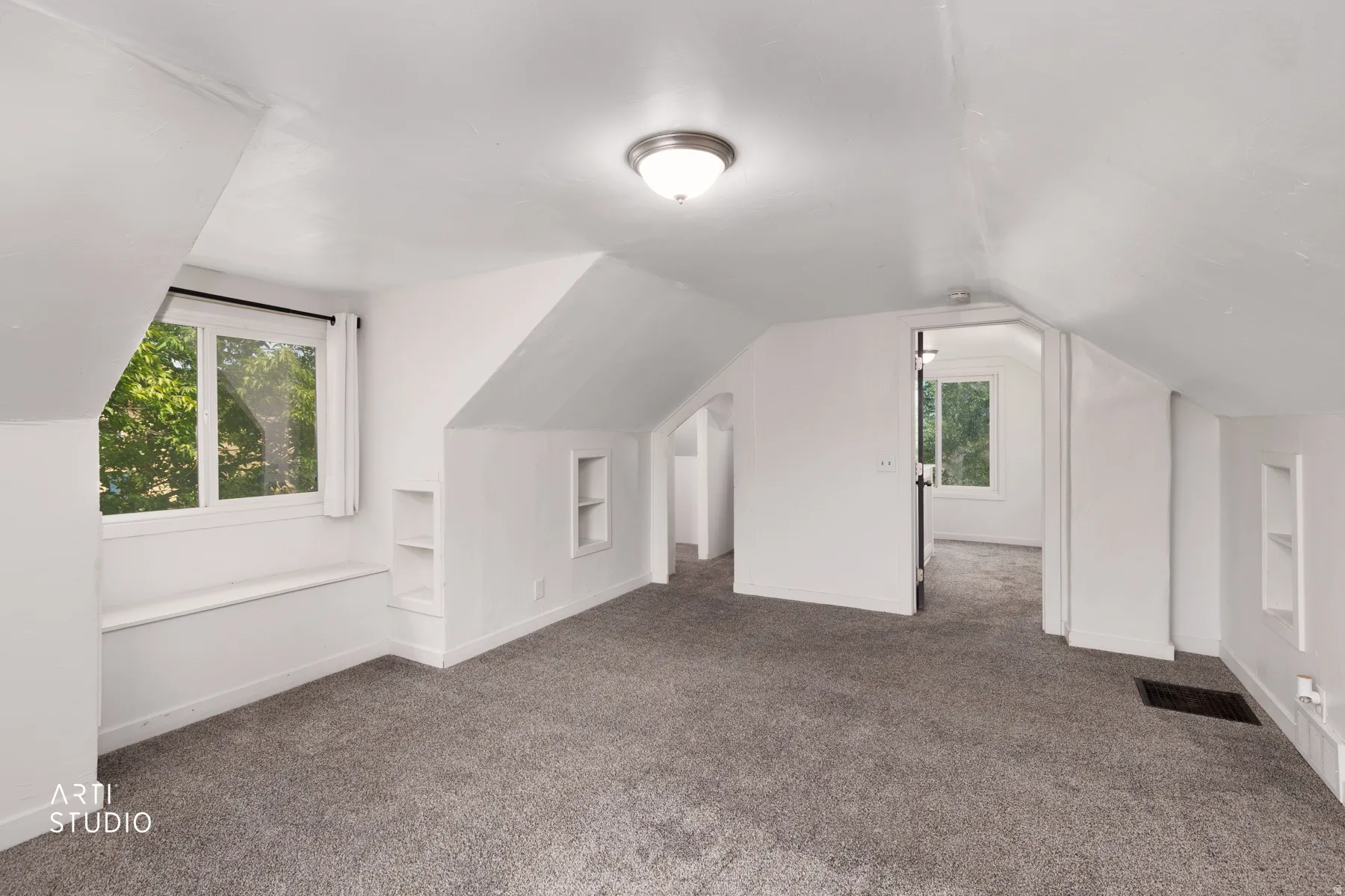 Carpeted room with sloped ceilings, recessed shelving, built-in window seating, and a flush-mount ceiling light fixture
