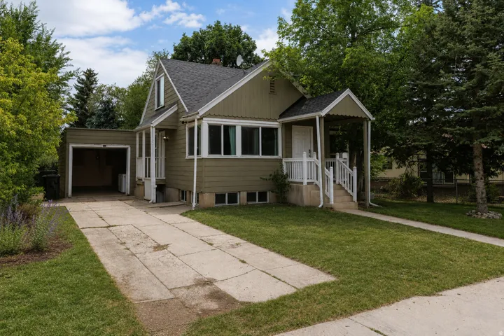 Gabled roofline, covered front entry, attached garage, concrete driveway, and mature landscaping