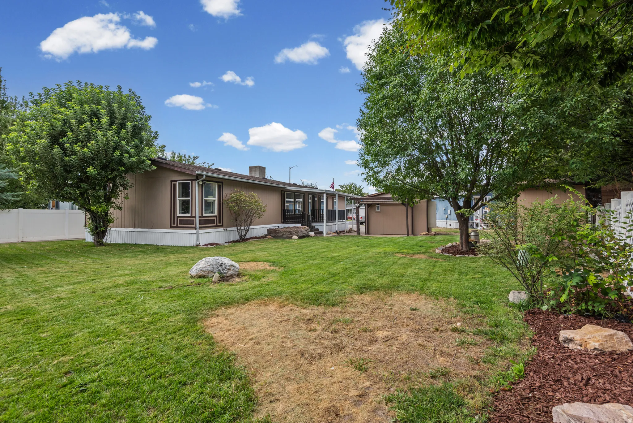 Spacious backyard featuring a manicured lawn, established shade trees, and a privacy fence