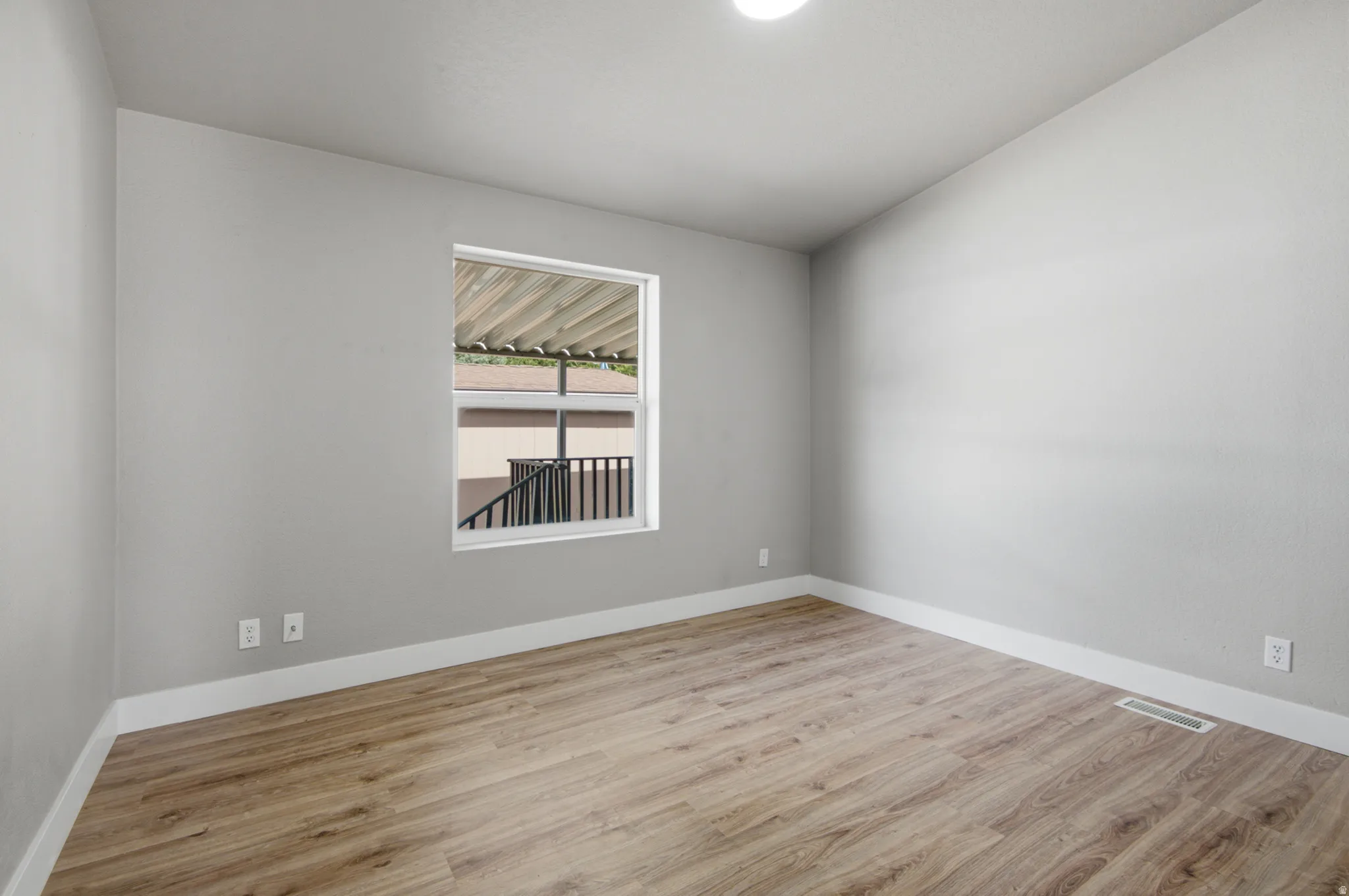 Neutral wall tones, wood-finish flooring, white trim, and a window with natural light