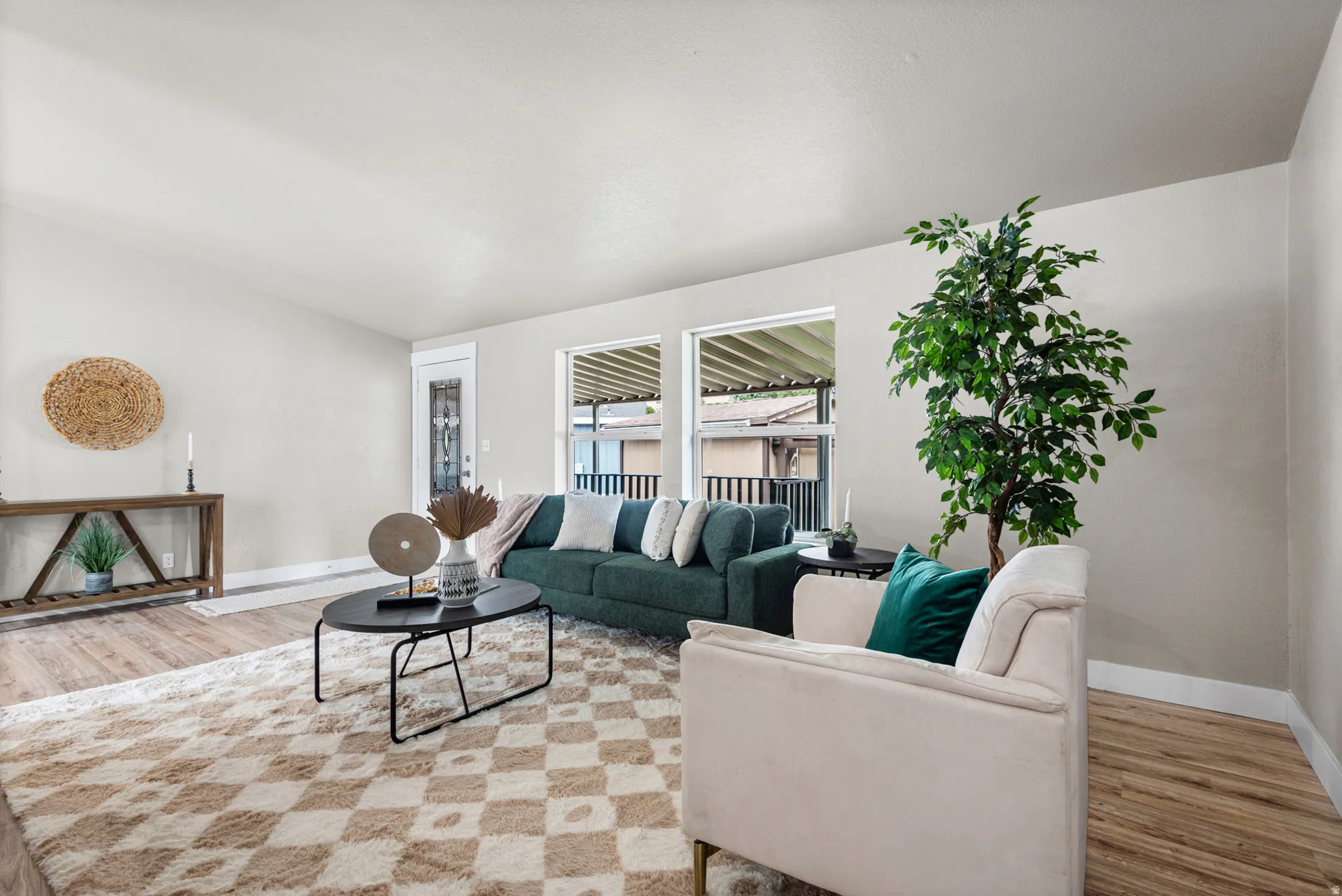 Spacious living area featuring wood-finish flooring, neutral wall tones, and large windows