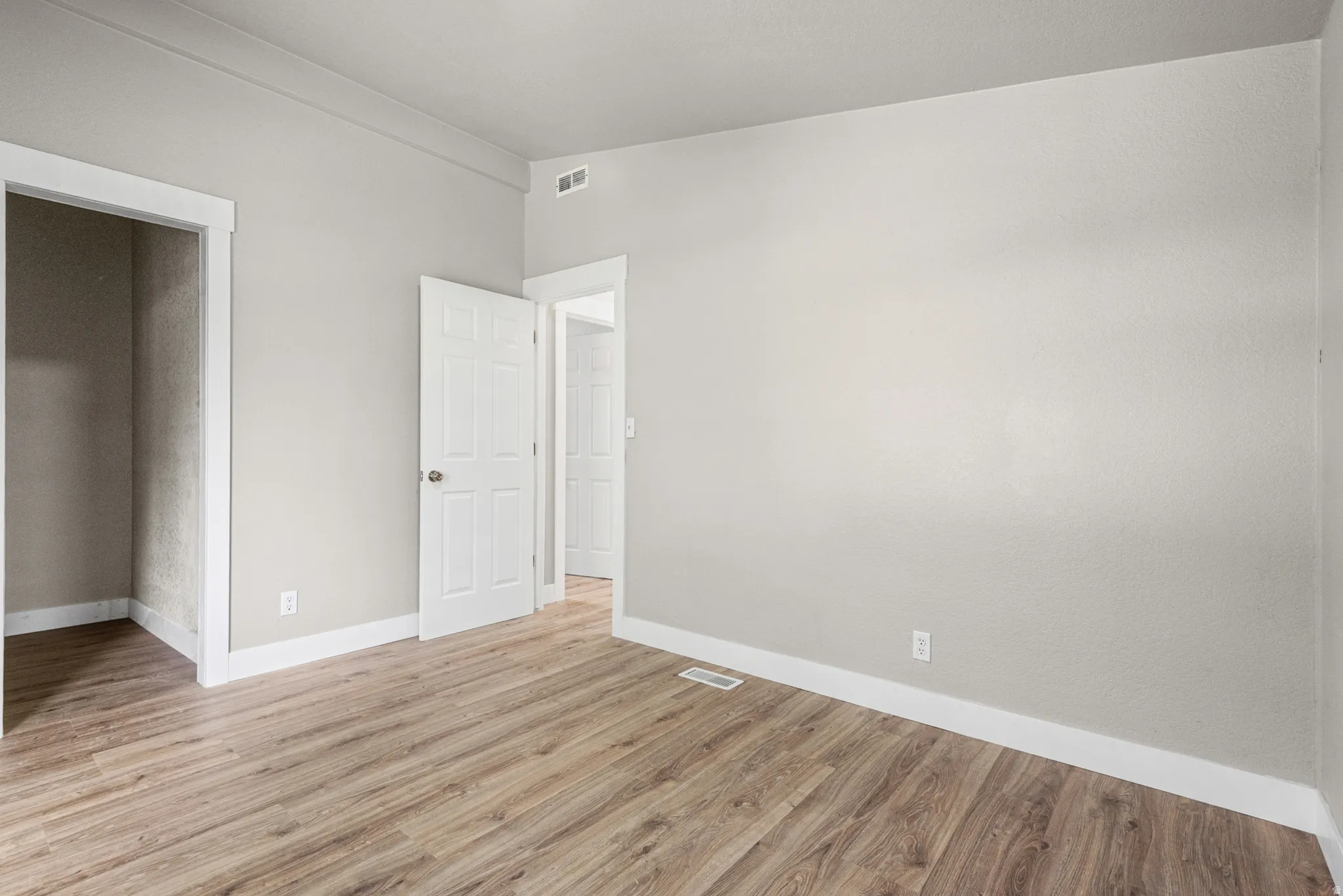 Neutral tone wall paint with crisp white trim, wood-finish flooring, and white paneled doors