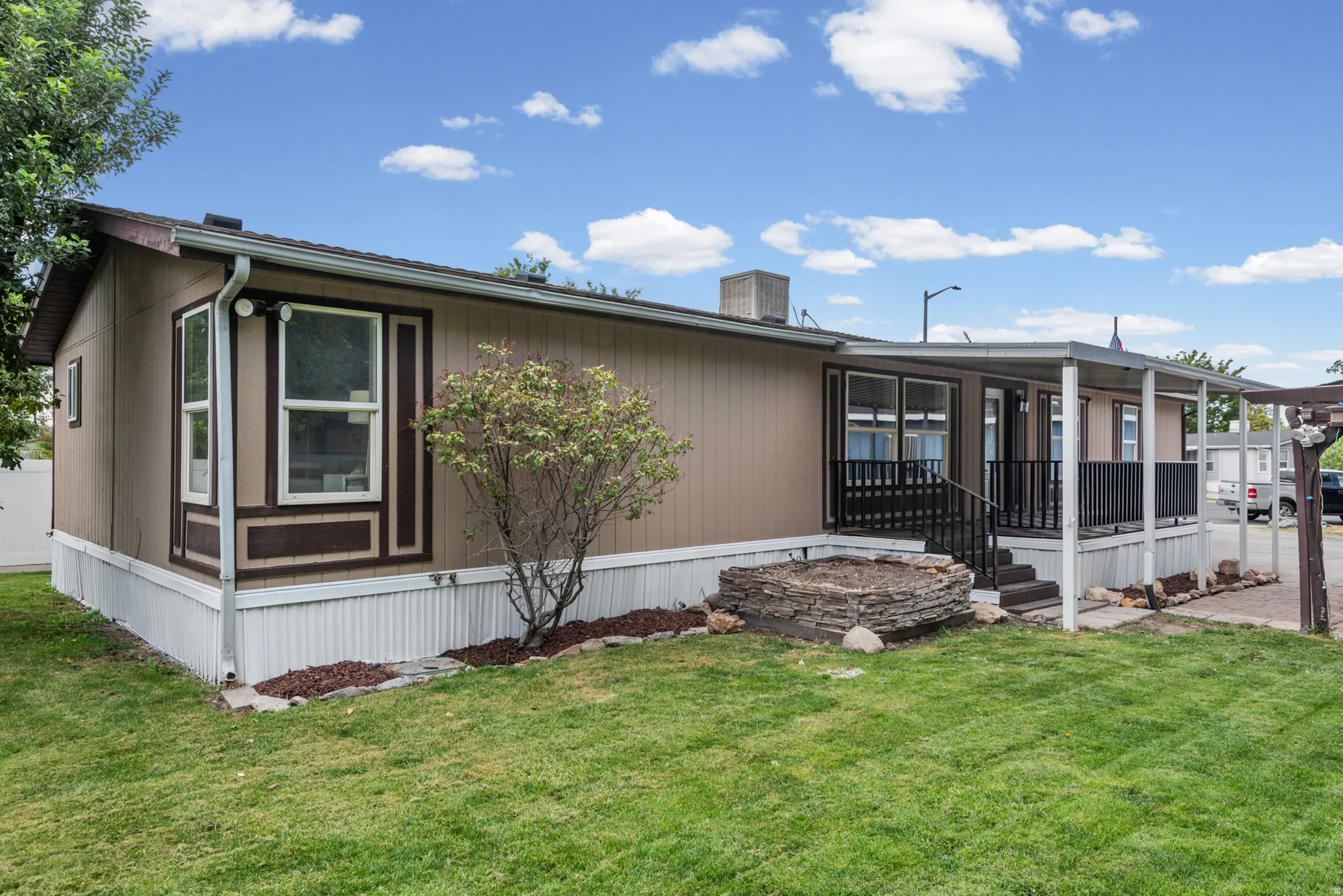 Exterior featuring a covered porch, bay window, landscaped rock bed, and manicured lawn