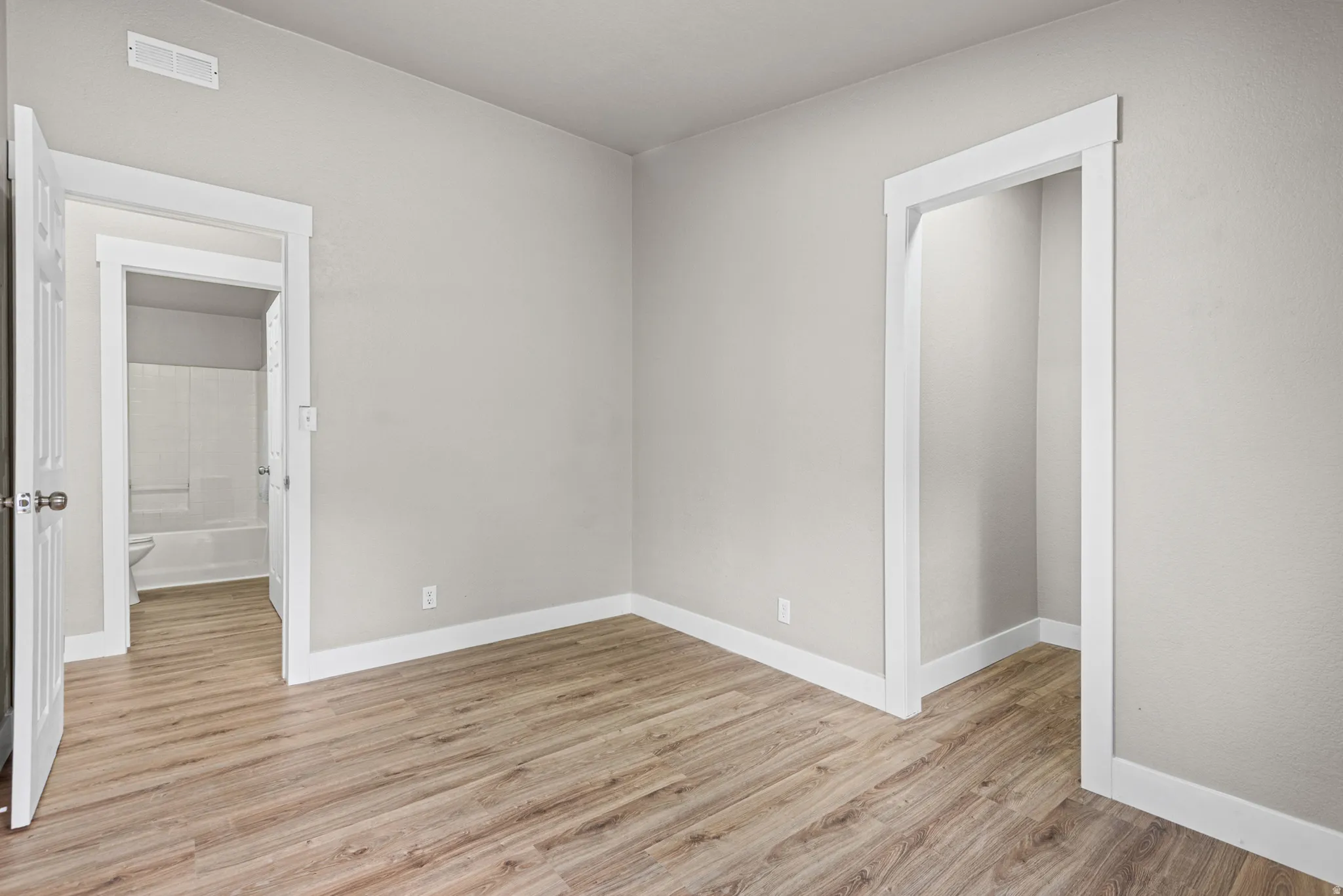 Wood-finish flooring, white baseboards, and neutral wall tones