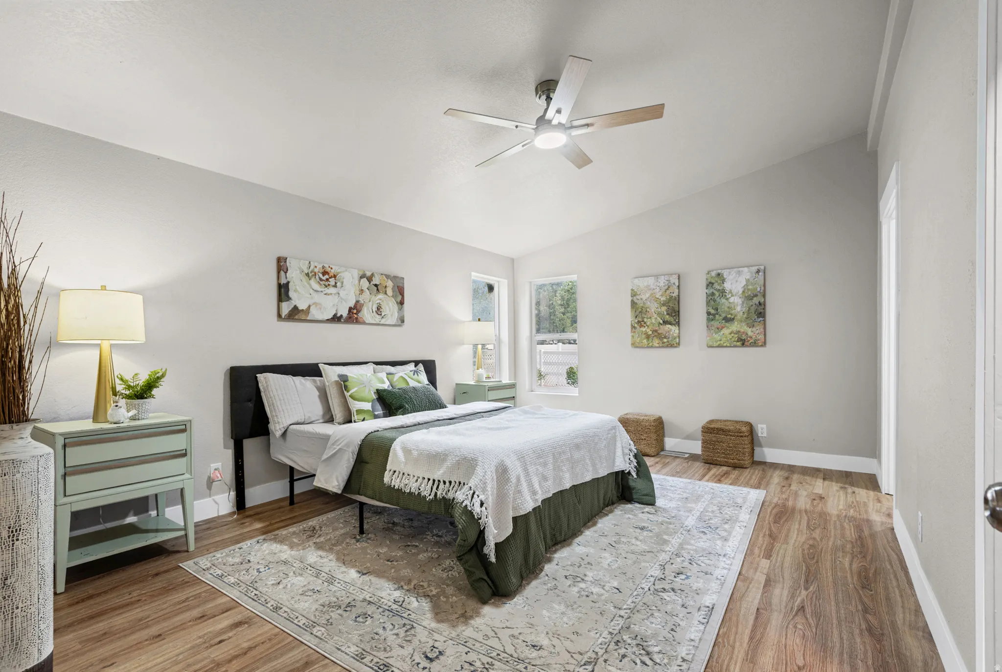 Vaulted ceiling with a ceiling fan, wood-finish flooring, and multiple windows