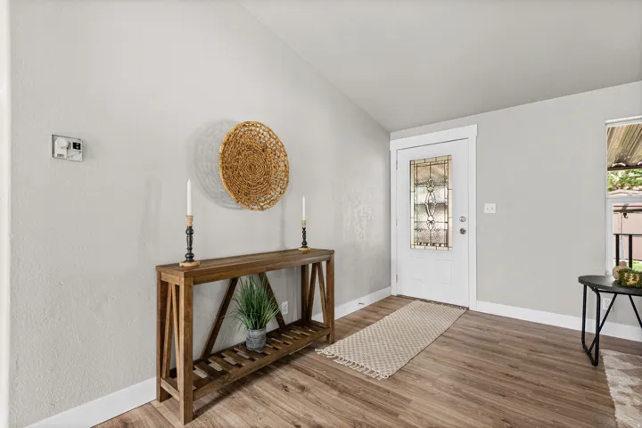Entryway featuring a decorative front door with leaded glass, wood-finish flooring, and a vaulted ceiling