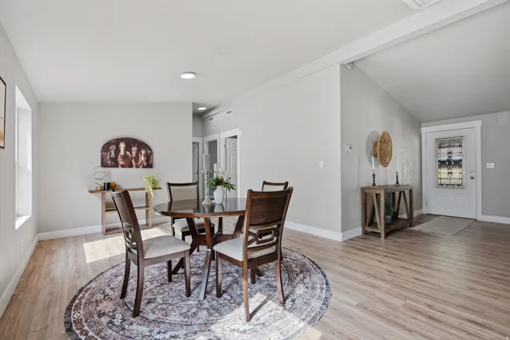 Spacious dining area featuring wood-finish flooring, recessed lighting, and an entryway with a decorative glass door