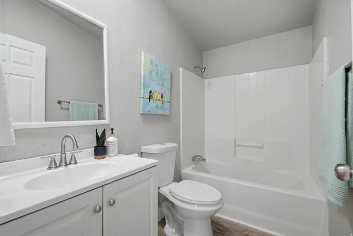Bright bathroom featuring a white vanity with dual-sink configuration, quartz countertop, brushed nickel fixtures, and a large framed mirror