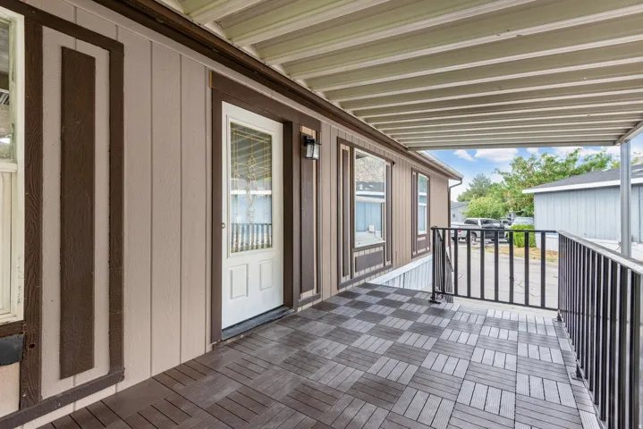 Covered porch with patterned tile flooring, a white paneled entry door with decorative glass, and contrasting exterior siding