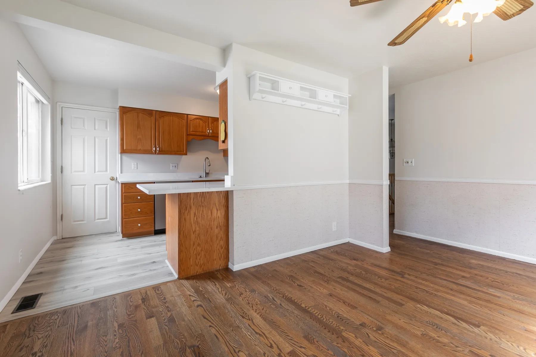 Kitchen area with wood cabinetry, light-toned countertops, and a stainless steel sink