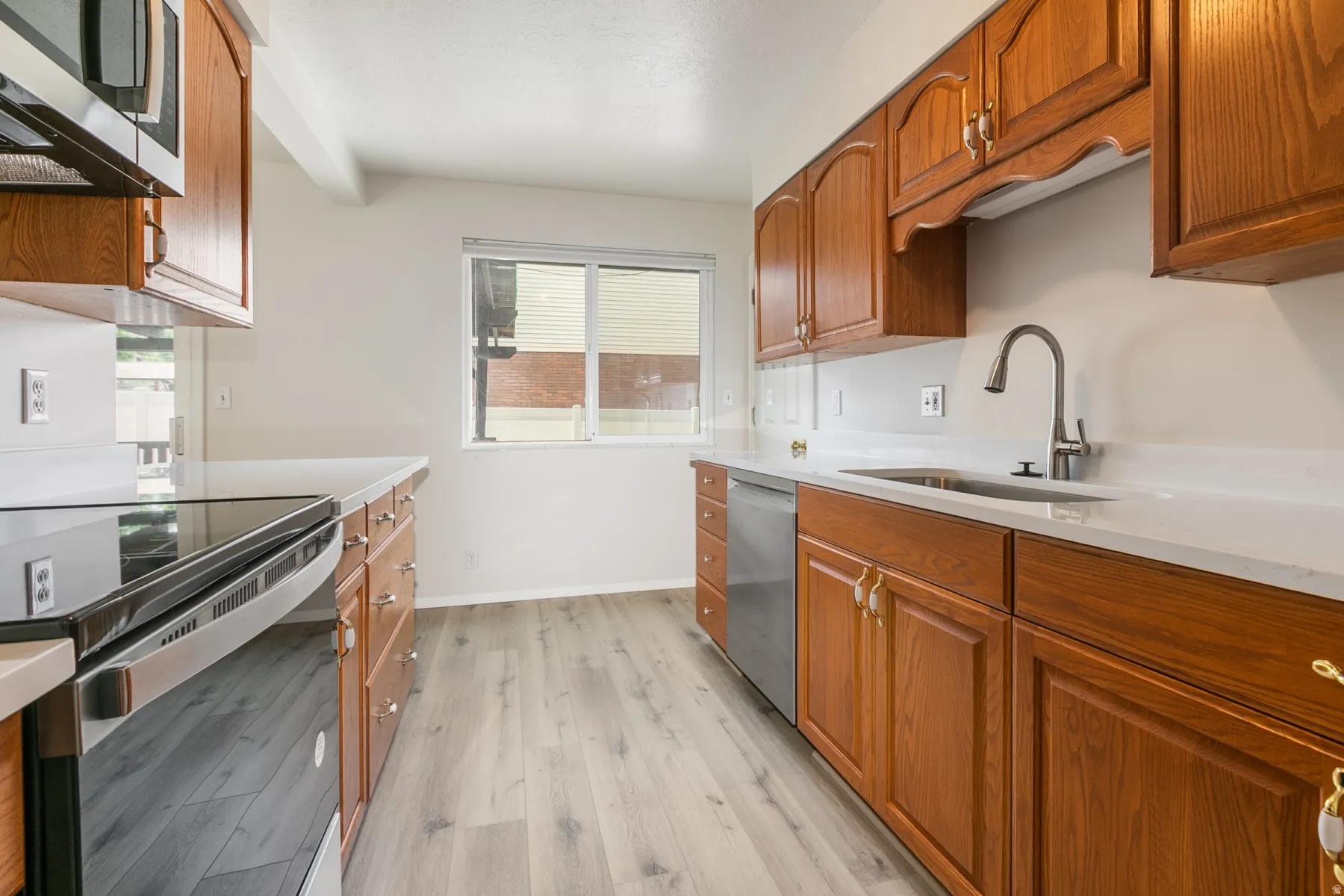 Kitchen featuring wood-finish cabinetry, light-toned countertops, and stainless steel appliances