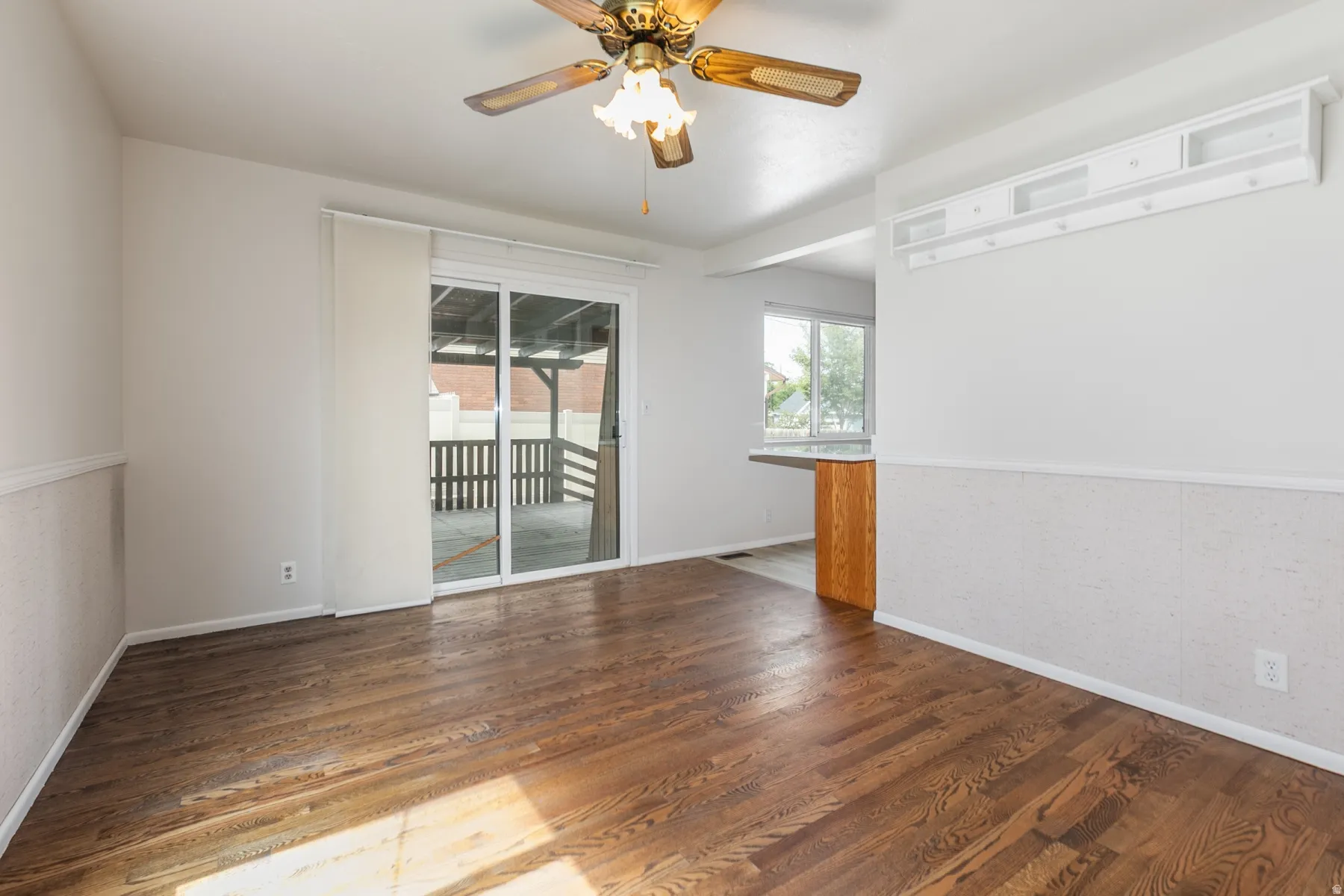 Wood-finish flooring, sliding glass door, overhead ceiling fan, built-in shelving, and a half-wall counter