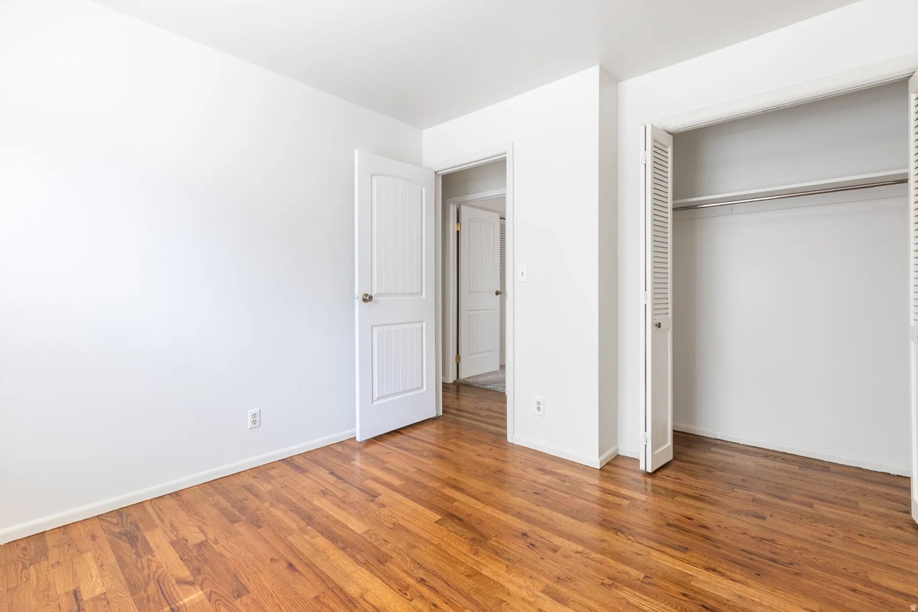 Hardwood flooring, white walls, white trim, bifold closet doors, and interior doors