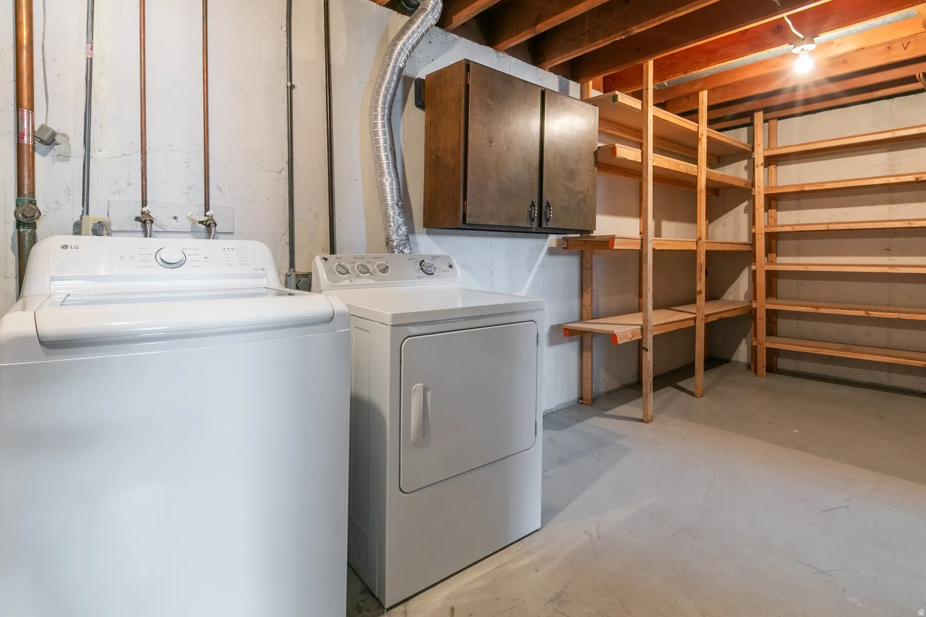 Laundry area featuring a washer and dryer, built-in wooden shelving, and exposed ceiling joists
