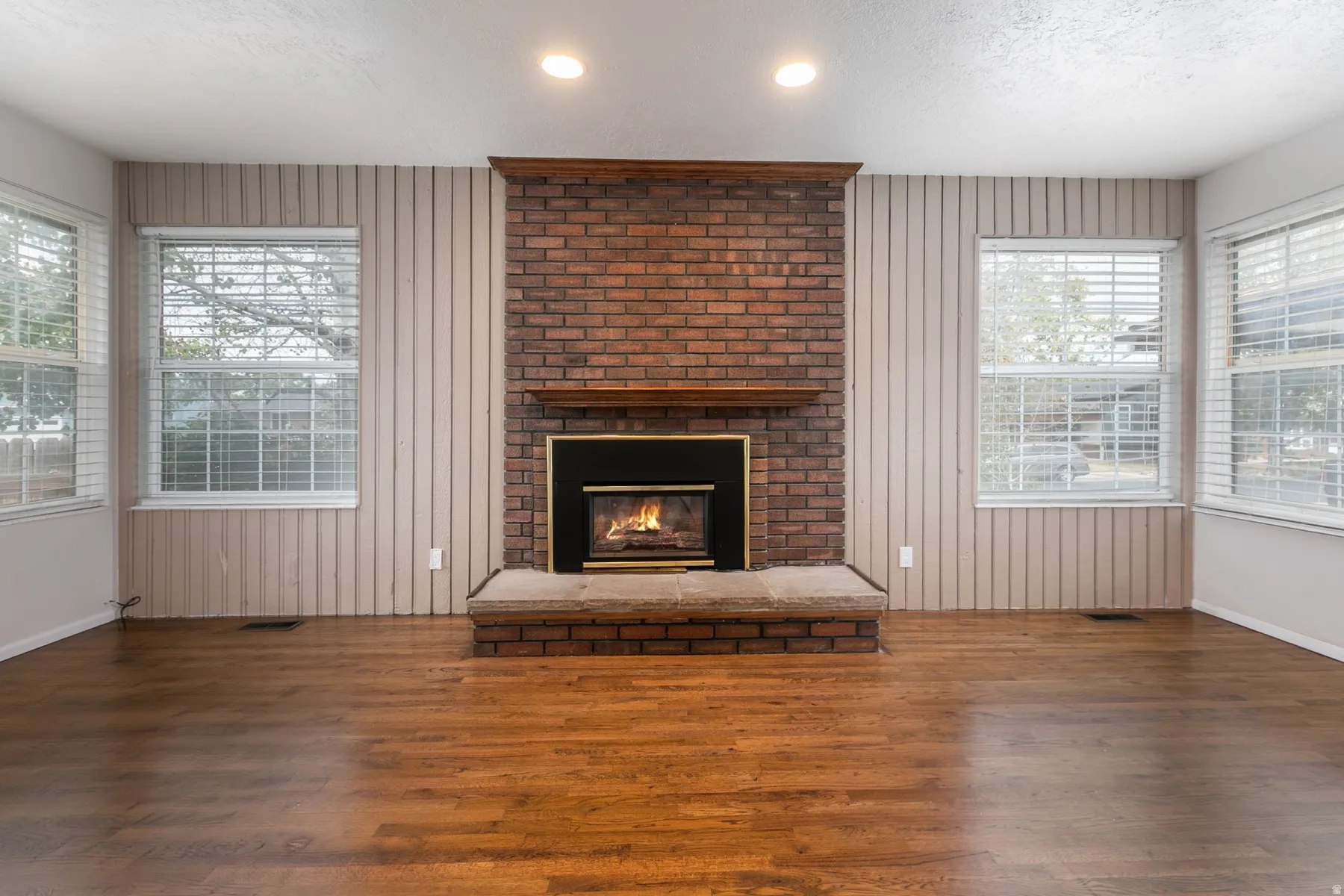 Brick fireplace with a wood mantel, raised hearth, and metal firebox