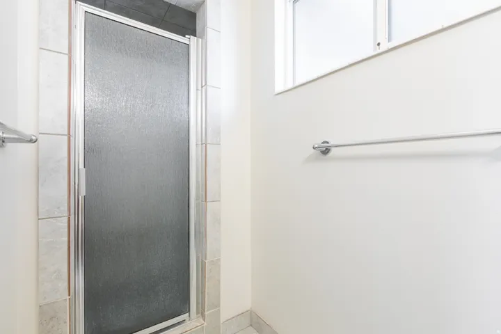 Textured glass shower enclosure with a stainless steel frame and tile surround