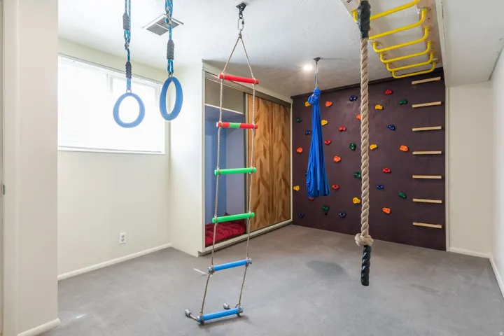 Wall-mounted rock climbing holds, integrated ceiling-mounted rings, an installed rope climb, and a built-in climbing ladder