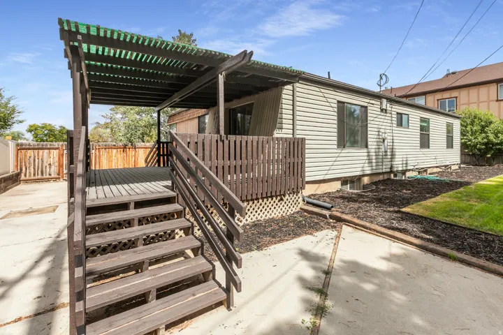 Wood deck with pergola, privacy fencing, and a manicured lawn
