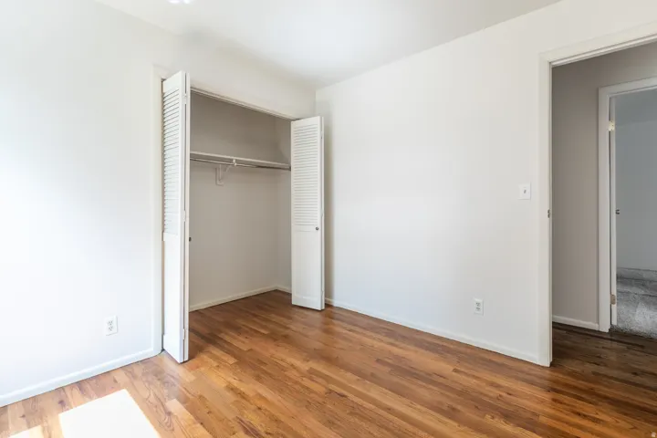 Hardwood flooring, white walls, louvered bi-fold closet doors, built-in closet shelving