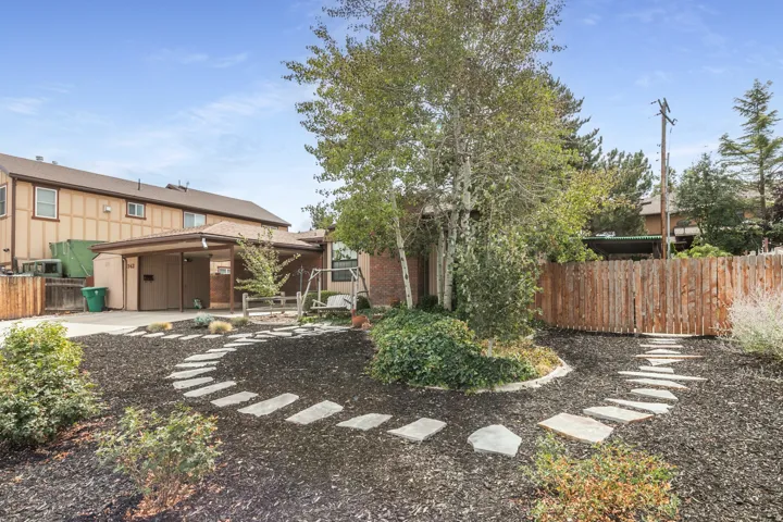 Concrete paver walkway with a covered carport and a wood privacy fence