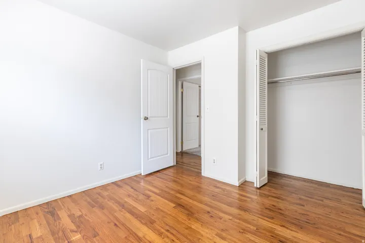 Hardwood flooring, white walls, white trim, bifold closet doors, and interior doors